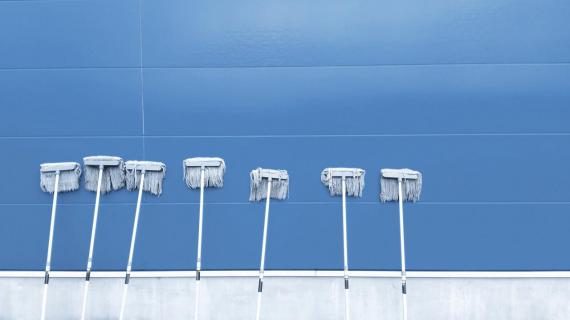 Ilustración equipo de limpieza, un conjunto de barredoras reposan sobre una pared