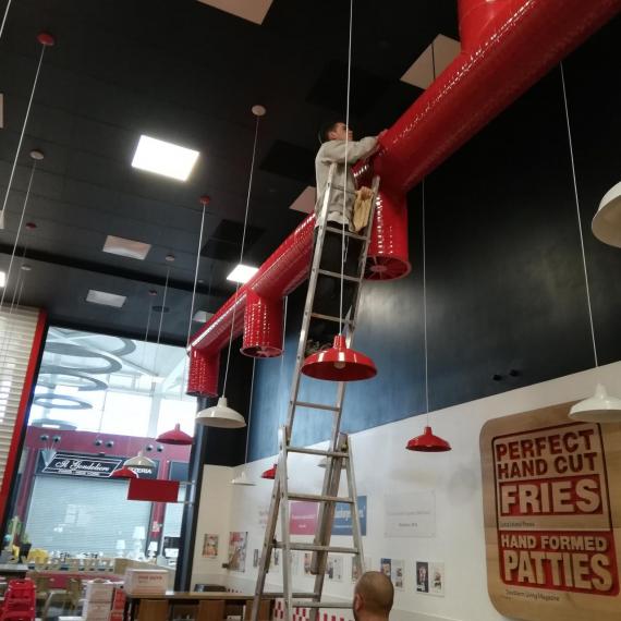 Un operario de mantenimiento limpia las zonas altas de un local comercial en Granada